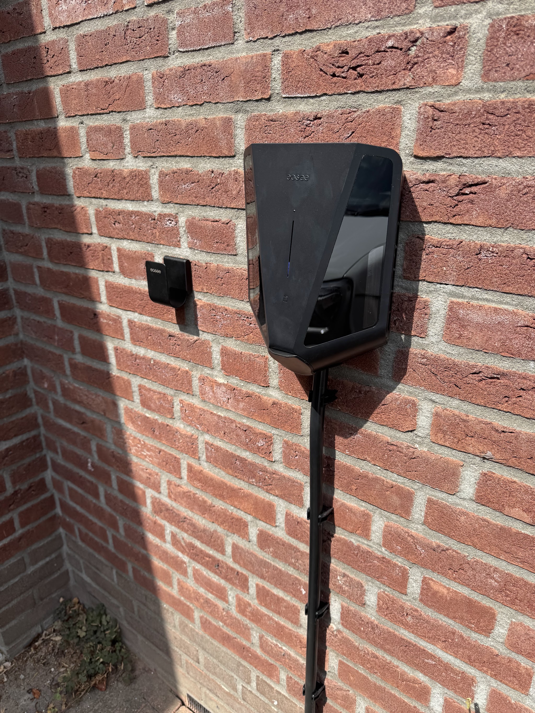Zwarte laadpaal op een rode bakstenen muur