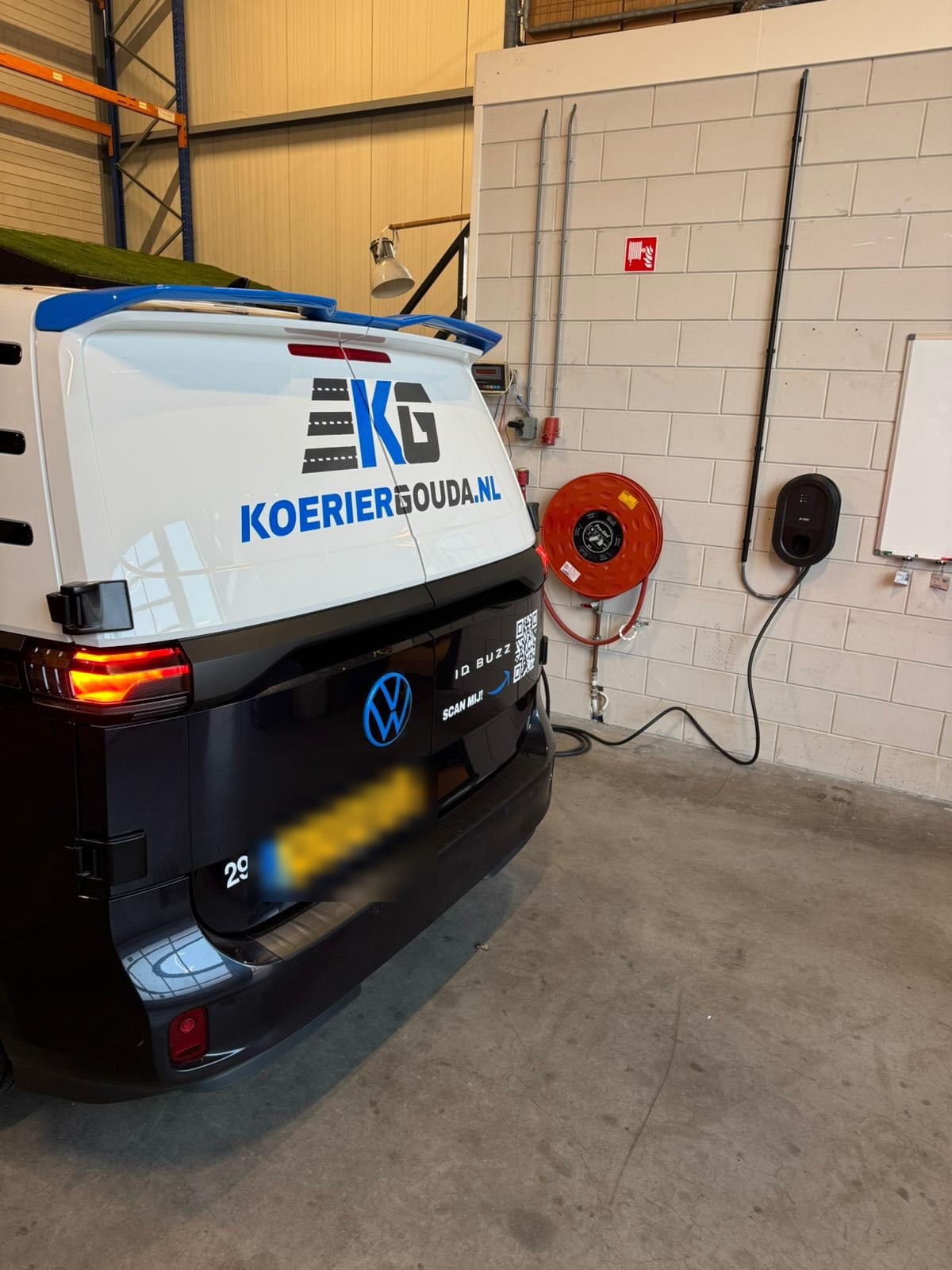 Laadpaal in de bedrijfshal van KoerierGouda, naast hun elektrische bus